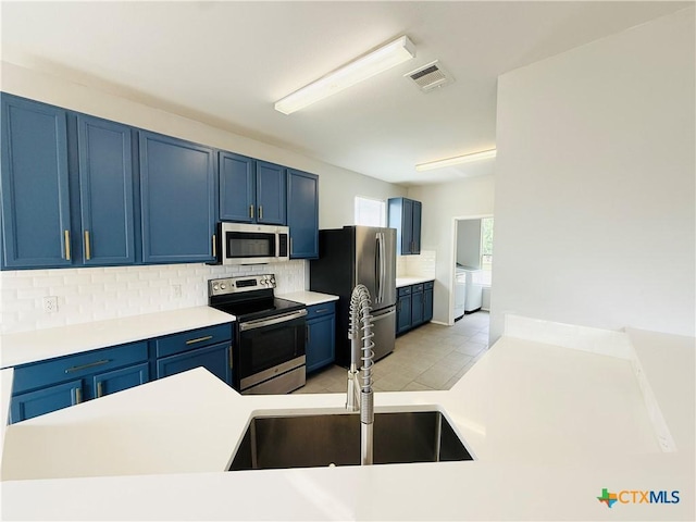 4302 Jack Barnes Ave, Killeen, TX 76549 - kitchen featuring stainless steel appliances, blue cabinetry, tasteful backsplash, independent washer and dryer, and light countertops