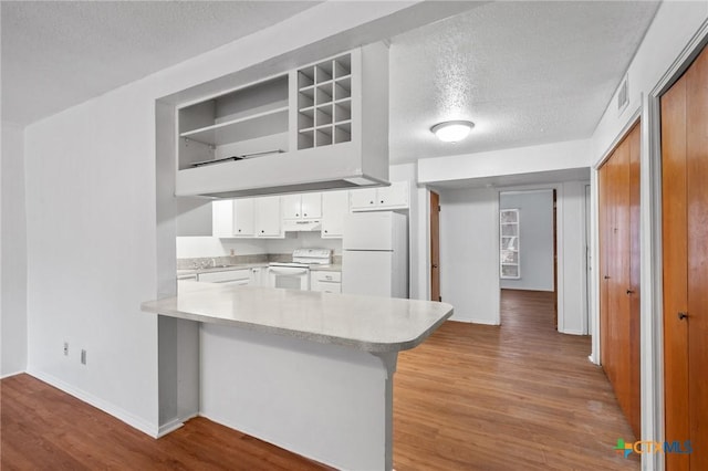 kitchen featuring white appliances, light hardwood / wood-style floors, kitchen peninsula, and white cabinets