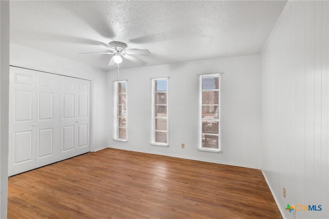 unfurnished bedroom with hardwood / wood-style flooring, ceiling fan, a closet, and a textured ceiling