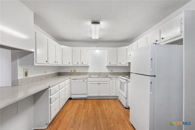 kitchen featuring sink, light wood-type flooring, white cabinets, white appliances, and a textured ceiling