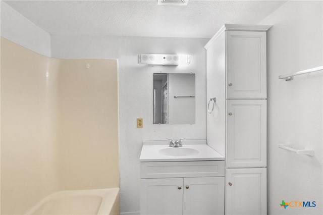 bathroom featuring vanity, bathing tub / shower combination, and a textured ceiling