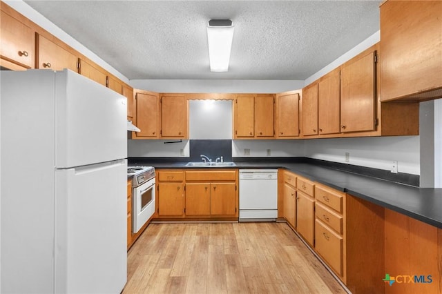 kitchen featuring sink, white appliances, light hardwood / wood-style floors, and a textured ceiling