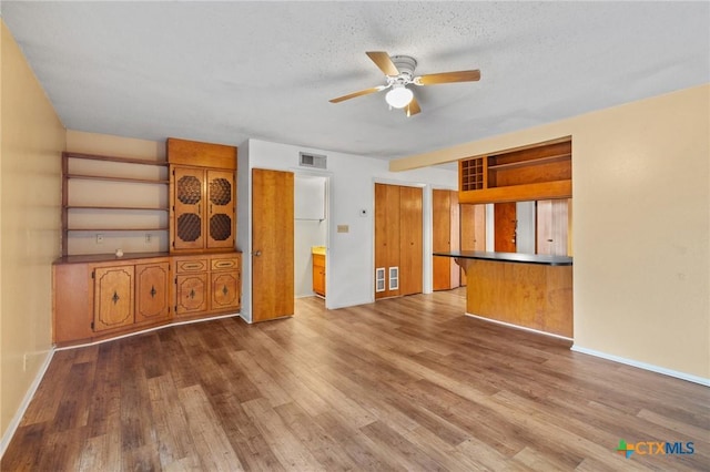 unfurnished living room with hardwood / wood-style flooring, a textured ceiling, and ceiling fan