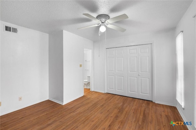 unfurnished bedroom with hardwood / wood-style flooring, ceiling fan, a closet, and a textured ceiling