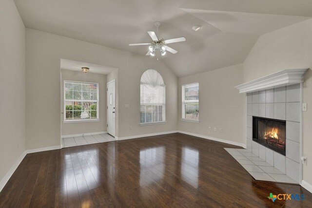 2121 Keystone Dr, New Braunfels, TX 78130 - unfurnished living room featuring a ceiling fan, wood finished floors, a tiled fireplace, vaulted ceiling, and baseboards