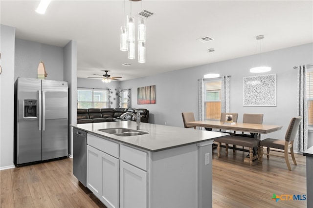 421 Perfect World Loop, Jarrell, TX 76537 - kitchen featuring appliances with stainless steel finishes, a sink, light wood finished floors, white cabinetry, and a center island with sink