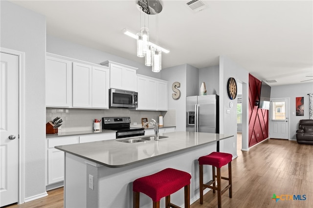 421 Perfect World Loop, Jarrell, TX 76537 - kitchen featuring appliances with stainless steel finishes, tasteful backsplash, light wood-style floors, a sink, and open floor plan