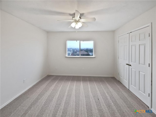 carpeted spare room with ceiling fan