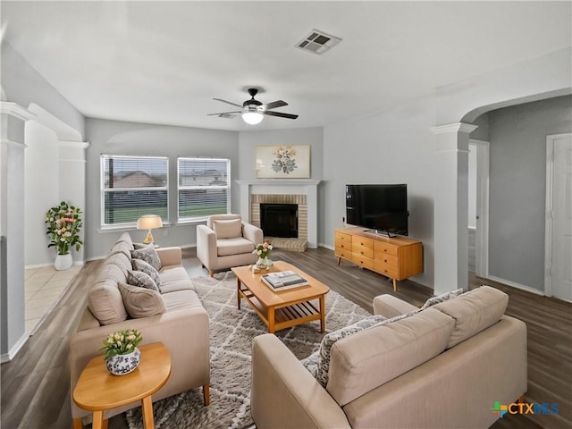 living room featuring ornate columns, ceiling fan, a fireplace, and wood-type flooring