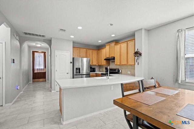 kitchen featuring sink, stainless steel appliances, tasteful backsplash, kitchen peninsula, and light brown cabinetry