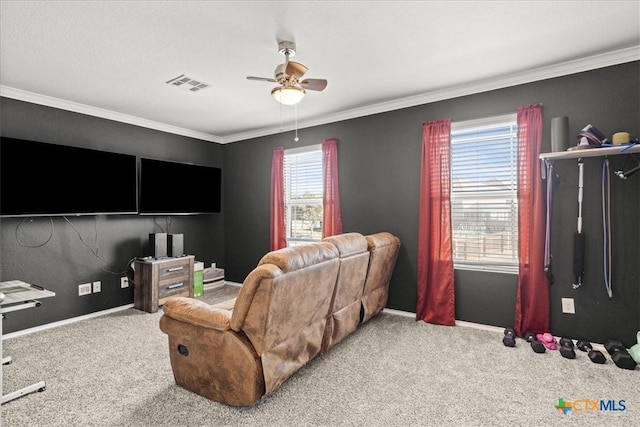 carpeted home theater room with baseboards, a ceiling fan, visible vents, and ornamental molding