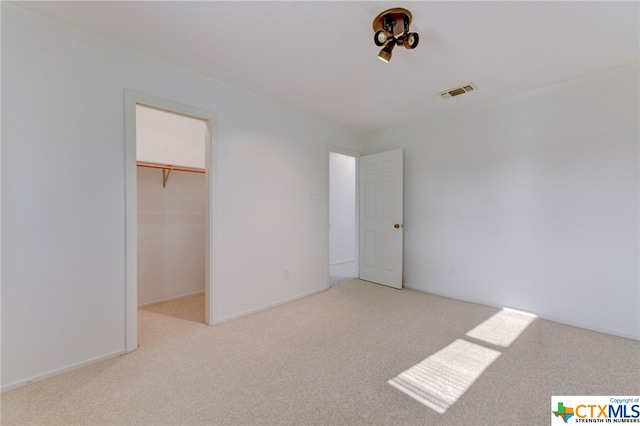 unfurnished bedroom with a closet, a walk in closet, and light carpet