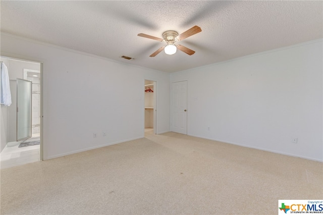 unfurnished room with a textured ceiling, light carpet, ceiling fan, and crown molding