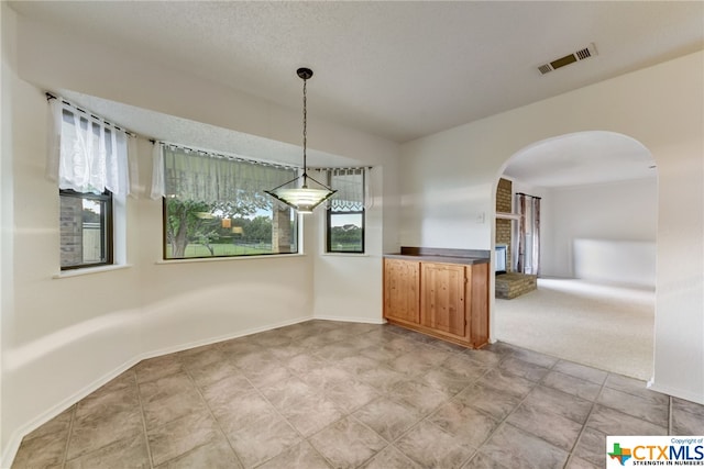 unfurnished dining area featuring carpet flooring and a textured ceiling