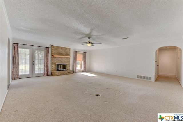 unfurnished living room with ceiling fan, a textured ceiling, light carpet, and french doors