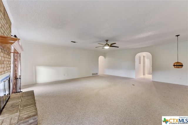 unfurnished living room with a textured ceiling, light colored carpet, ceiling fan, and a fireplace