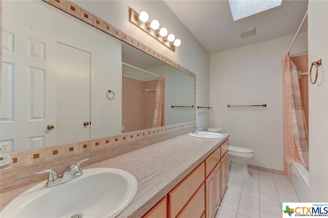 full bathroom with toilet, tile patterned flooring, a textured ceiling, vanity, and a skylight