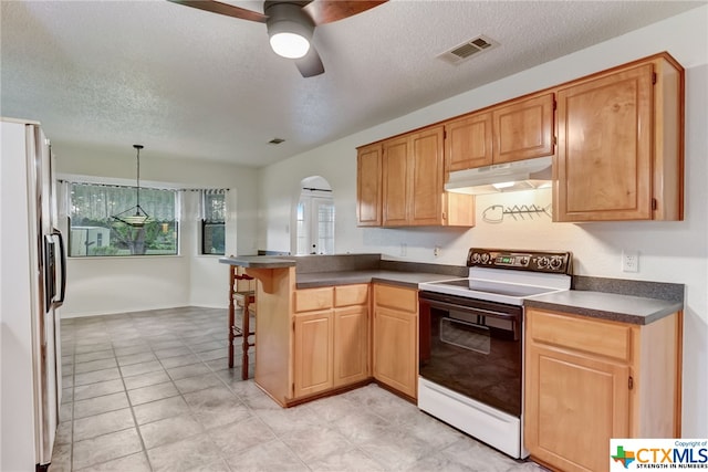 kitchen featuring kitchen peninsula, white appliances, a textured ceiling, and a breakfast bar