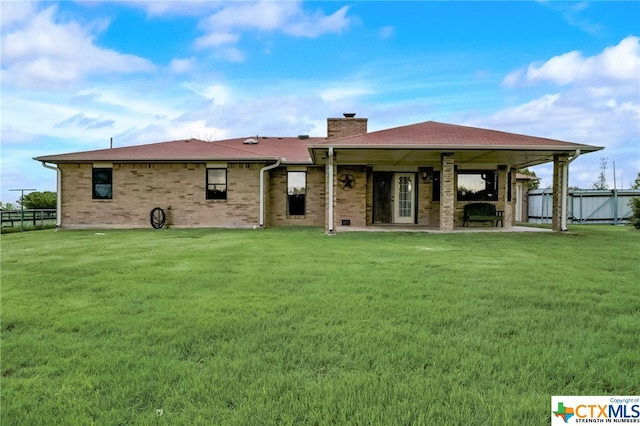 back of property with a lawn and a patio