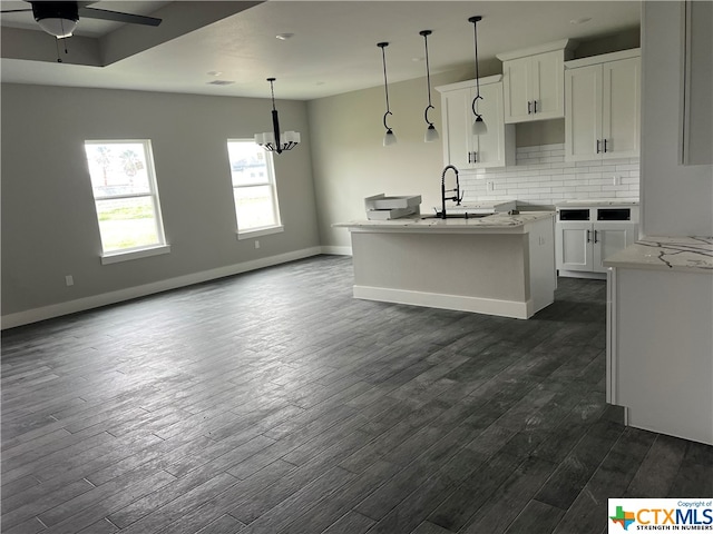 kitchen featuring a kitchen island with sink, dark wood-type flooring, white cabinets, and decorative light fixtures