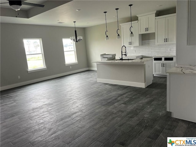 303 Claret, Port Lavaca, TX 77979 - kitchen featuring decorative backsplash, white cabinets, dark wood finished floors, and a kitchen island with sink