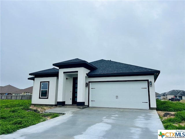 303 Claret, Port Lavaca, TX 77979 - view of front of home with an attached garage, concrete driveway, a shingled roof, and stucco siding