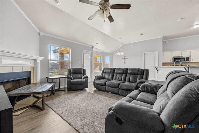 3705 Armstrong County Ct, Killeen, TX 76549 - living area featuring light wood-type flooring, ornamental molding, a ceiling fan, lofted ceiling, and a tile fireplace