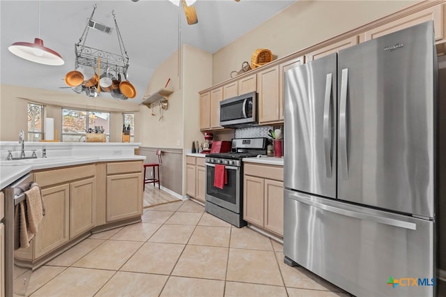 kitchen featuring appliances with stainless steel finishes, hanging light fixtures, light brown cabinetry, and light tile patterned floors