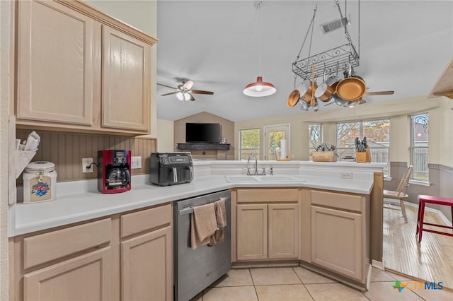 kitchen with kitchen peninsula, stainless steel dishwasher, light tile patterned floors, light brown cabinets, and sink