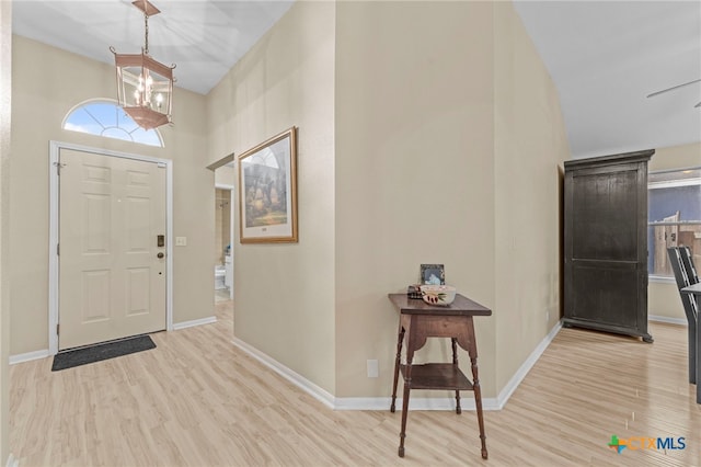 foyer entrance with ceiling fan with notable chandelier and light hardwood / wood-style flooring