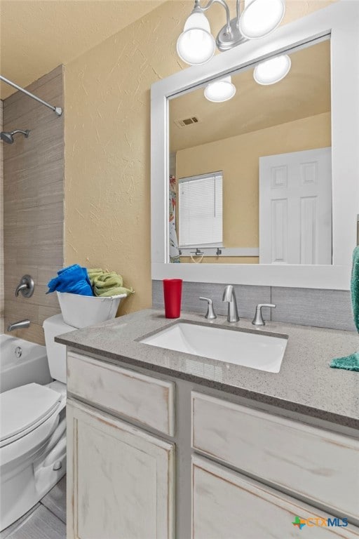 full bathroom featuring toilet, tiled shower / bath combo, and vanity