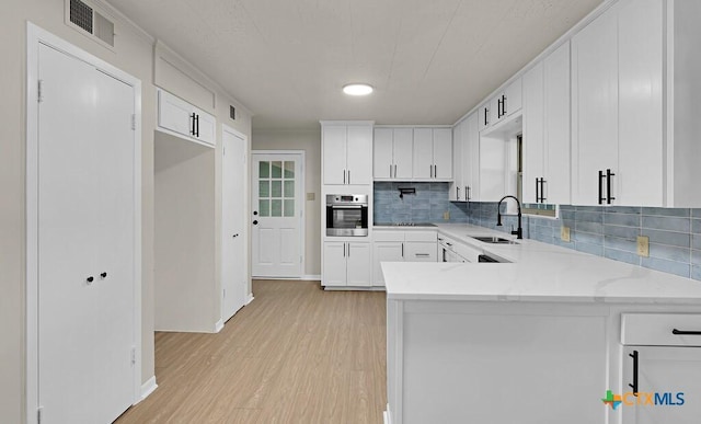 309 E Xavier Ave, Temple, TX 76501 - kitchen with stainless steel oven, backsplash, light wood-style floors, and a peninsula