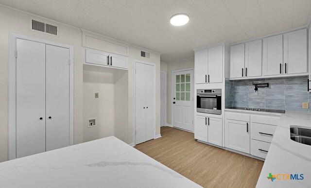 309 E Xavier Ave, Temple, TX 76501 - kitchen featuring stainless steel oven, light wood-style flooring, decorative backsplash, and white cabinetry