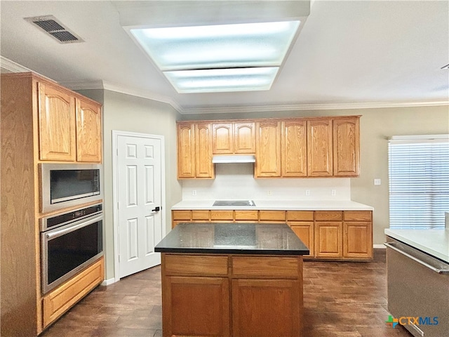 kitchen featuring crown molding, a kitchen island, dark wood-type flooring, and appliances with stainless steel finishes