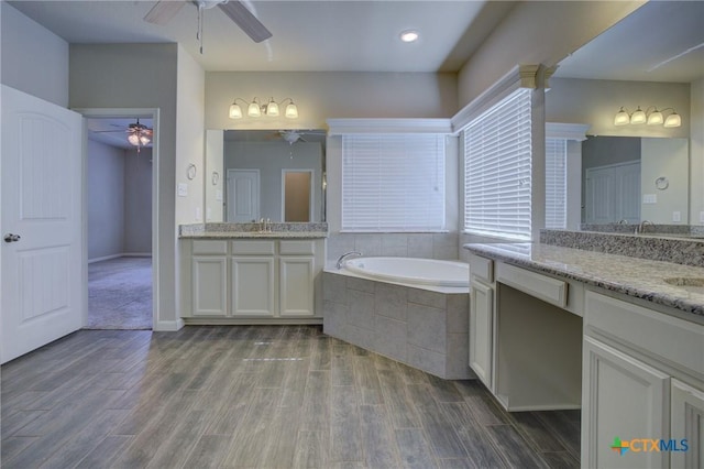 full bathroom with a ceiling fan, a garden tub, wood finished floors, and a sink