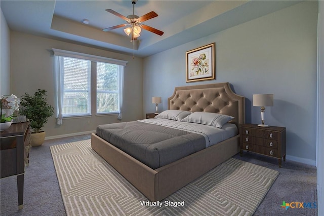 bedroom with carpet flooring, baseboards, and a tray ceiling