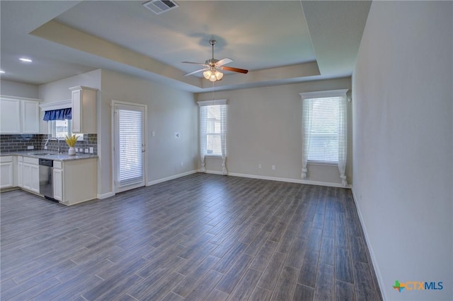 interior space featuring dark wood-style floors, visible vents, a tray ceiling, dishwasher, and backsplash