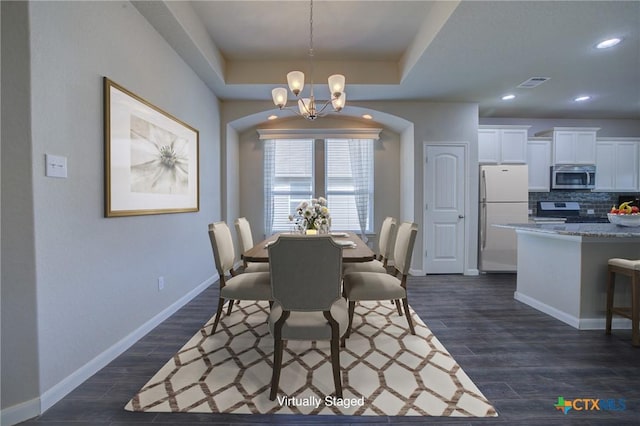 dining room featuring baseboards, visible vents, dark wood-style flooring, a raised ceiling, and a notable chandelier