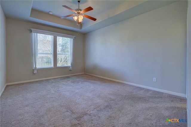 unfurnished room featuring baseboards, carpet, a tray ceiling, and a ceiling fan