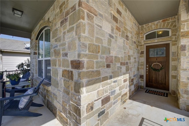 entrance to property featuring stone siding and covered porch