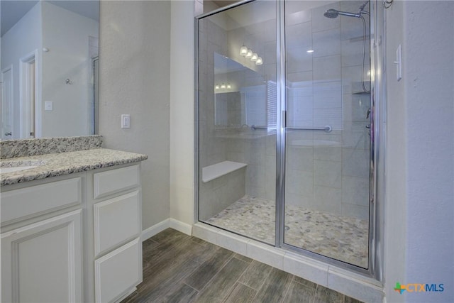 bathroom with a shower stall, vanity, baseboards, and wood tiled floor