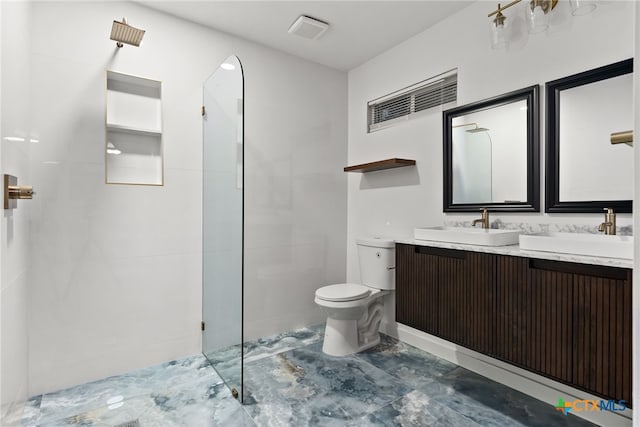 bathroom featuring toilet, tiled shower, and vanity