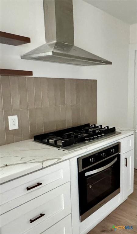 2802 Oakdale Dr, Temple, TX 76502 - kitchen featuring wall chimney exhaust hood, black oven, decorative backsplash, and white cabinets