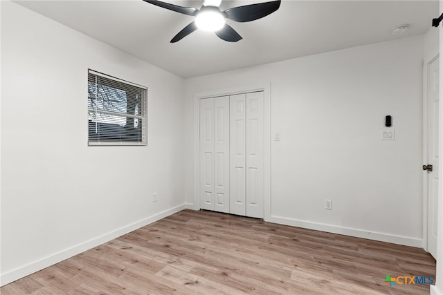 unfurnished bedroom with light wood-type flooring, ceiling fan, and a closet