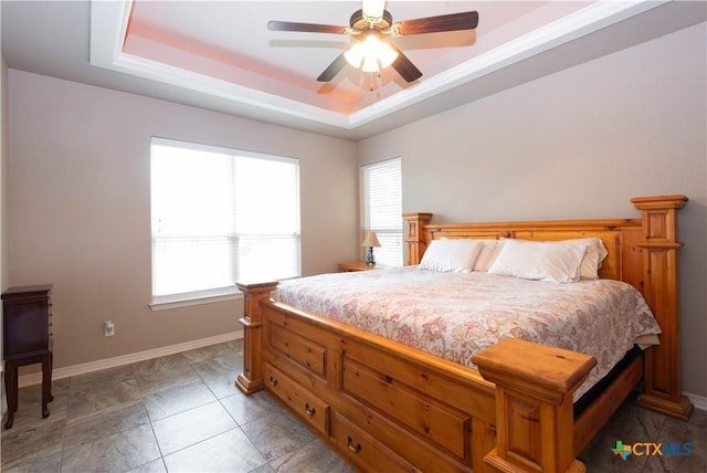 bedroom with ceiling fan, multiple windows, and a raised ceiling