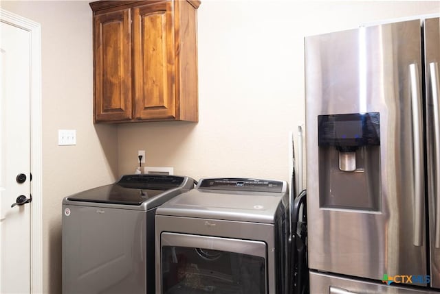 laundry area featuring washer and clothes dryer and cabinets