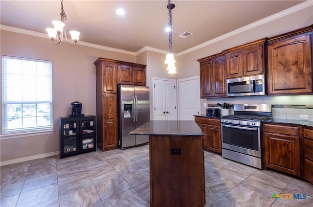 kitchen with a chandelier, a kitchen island, stainless steel appliances, and pendant lighting