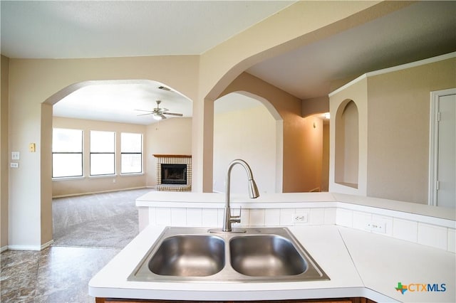 4607 Stanford Dr, Killeen, TX 76542 - kitchen featuring a sink, ceiling fan, a brick fireplace, light countertops, and arched walkways