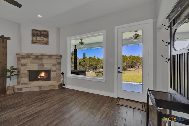 315 Hilltop Rdg, New Braunfels, TX 78132 - living room featuring wood finished floors, ceiling fan, baseboards, and a stone fireplace