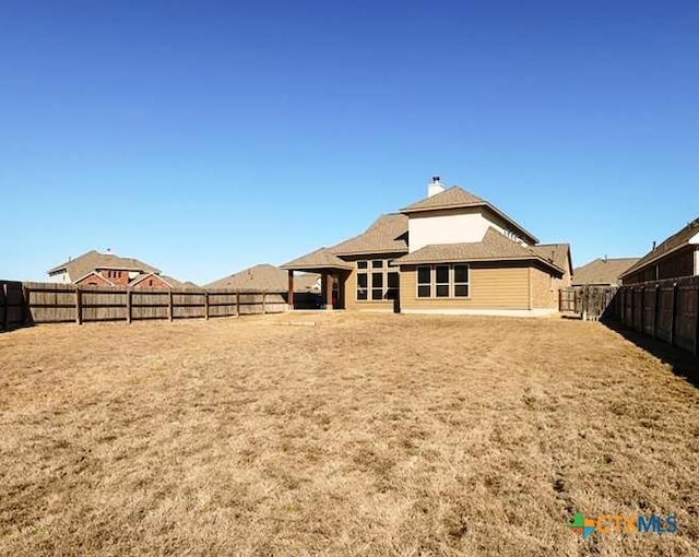 rear view of property with a fenced backyard and a chimney